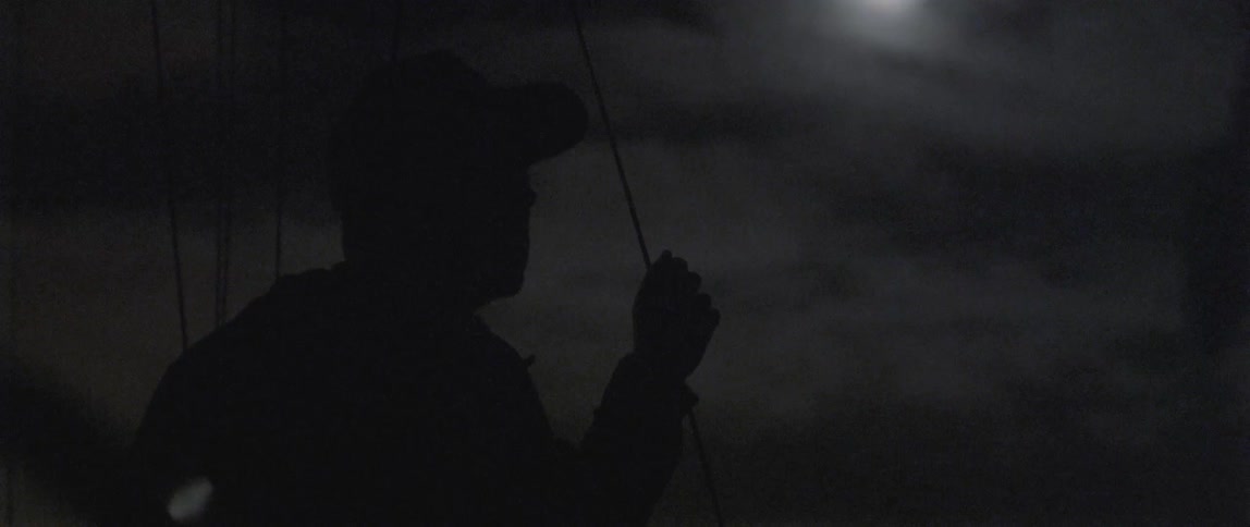 A man is standing on a boat at night