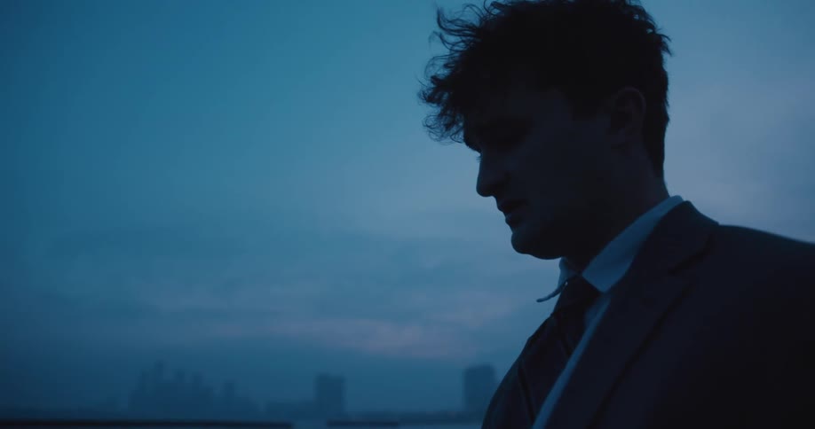 A distraught businessman looks at the city skyline at blue hour