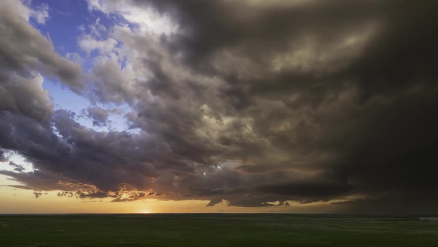 Thunderstorm over a plain green field during day time