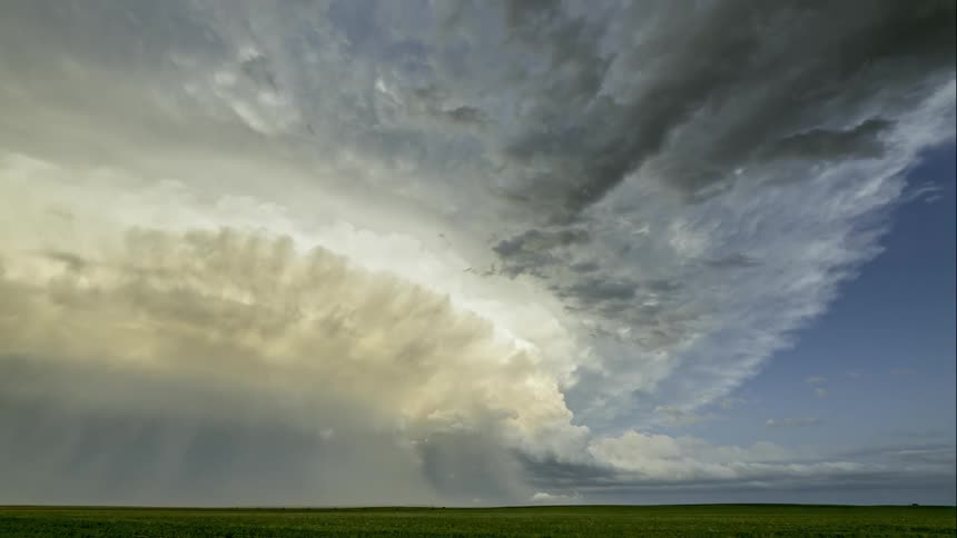 Time lapse of a bright sunny day over a wide open grass field as clouds roll over the land