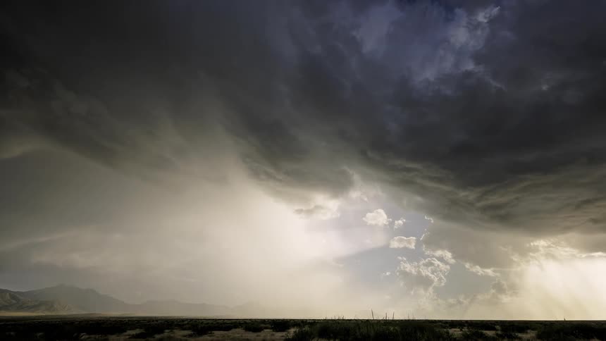 A big gray cloud passing through the sky where the sun is shining brightly