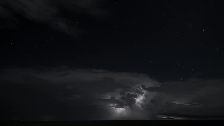 Time lapse of a lightning storm flashing in the cloudy sky at night lighting up the horizon