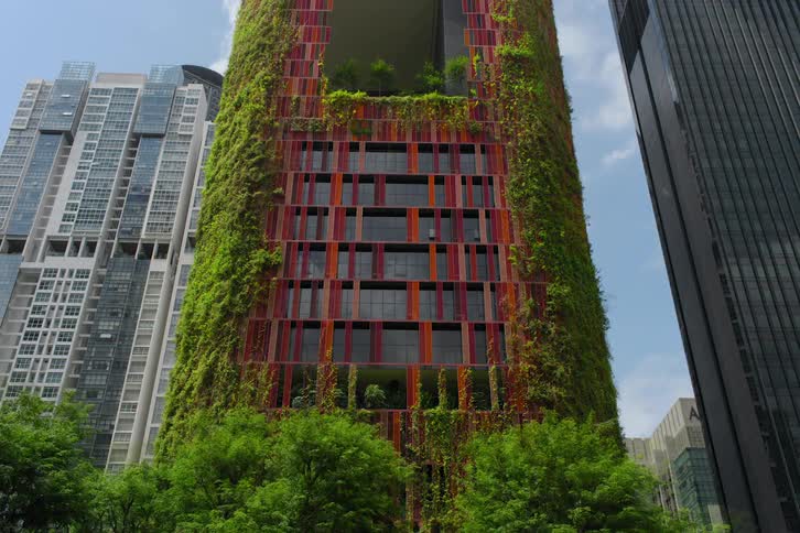 Red building with mirrored glass windows and plants growing around it