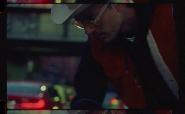 A man dressed in a hat and orange glasses trying to start his motorcycle