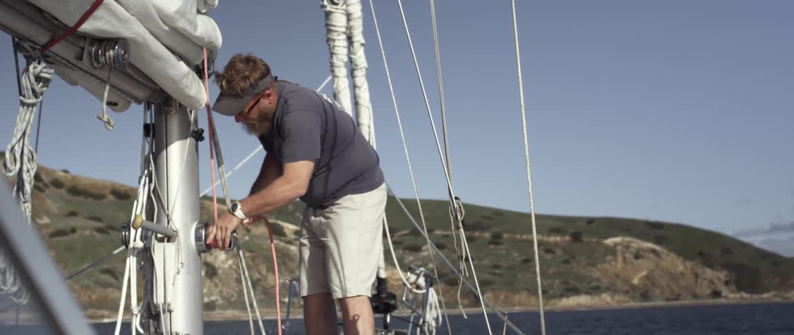 A man is tying rope on a ship