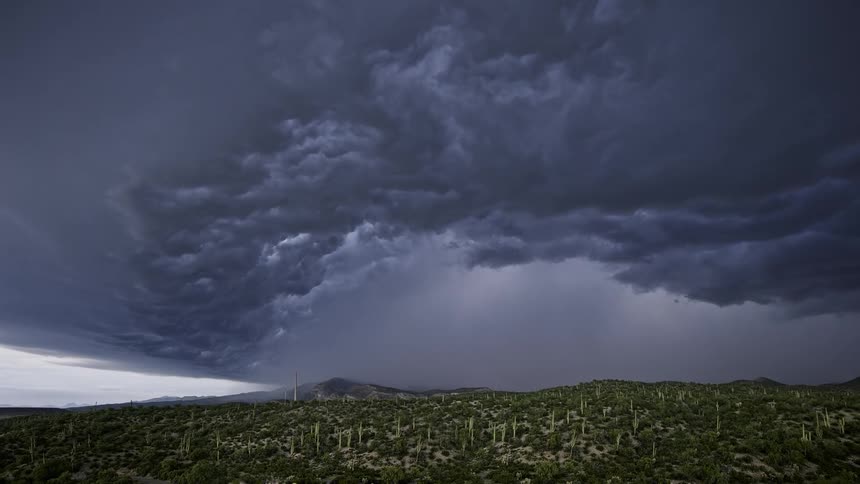 A huge gray cloud with lightning moves in the sky during a thunderstorm