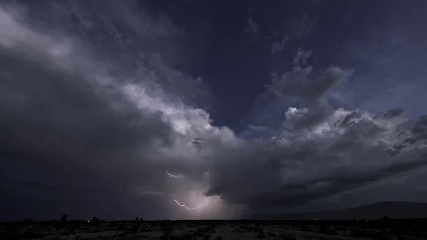 Time lapse of a thunderstorm with lightning flashing on the horizon as clouds roll through the dark sky
