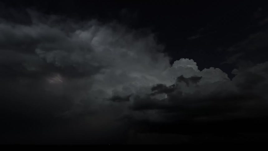 A thunderstorm with lightning flashing as large dark clouds move quickly across the sky