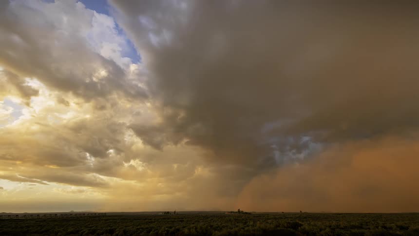A cloudy sky and dust storm forming over the flat land on a sunny day