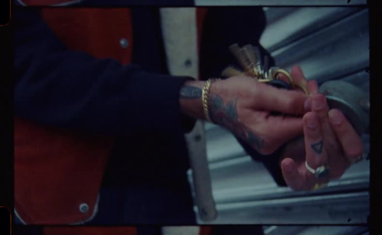 Close up of a mans hands using a key to unlock a padlock attached to a metal door