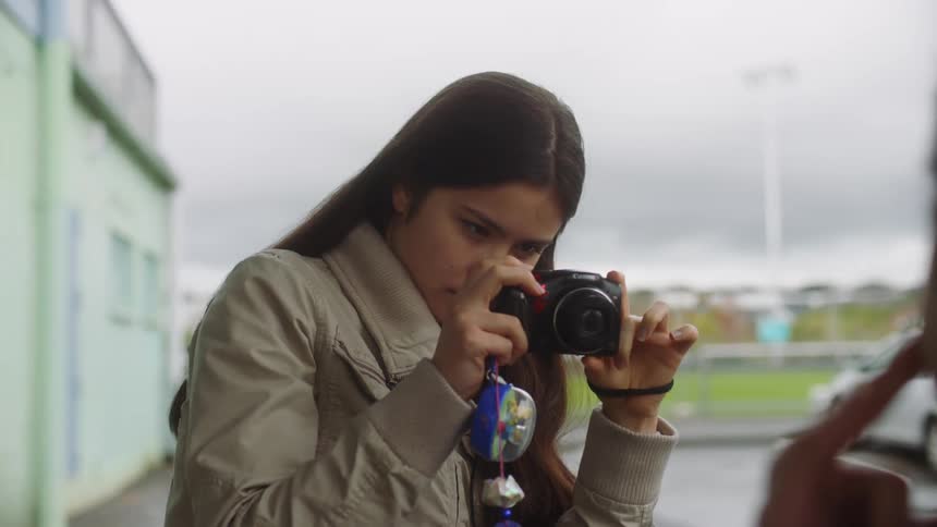 A woman taking a picture of a person in front of her and then laughing