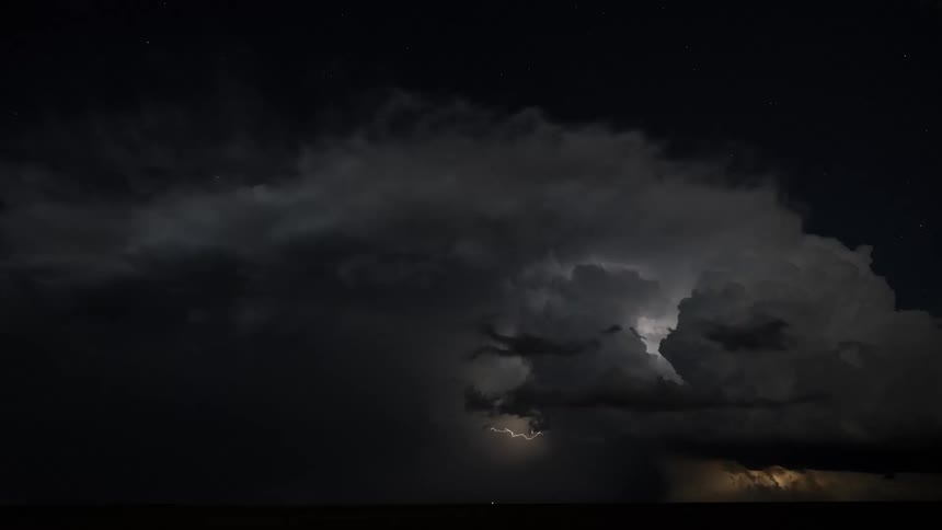 Time lapse of storm clouds rolling across the sky at night as lightning flashes lighting up the sky