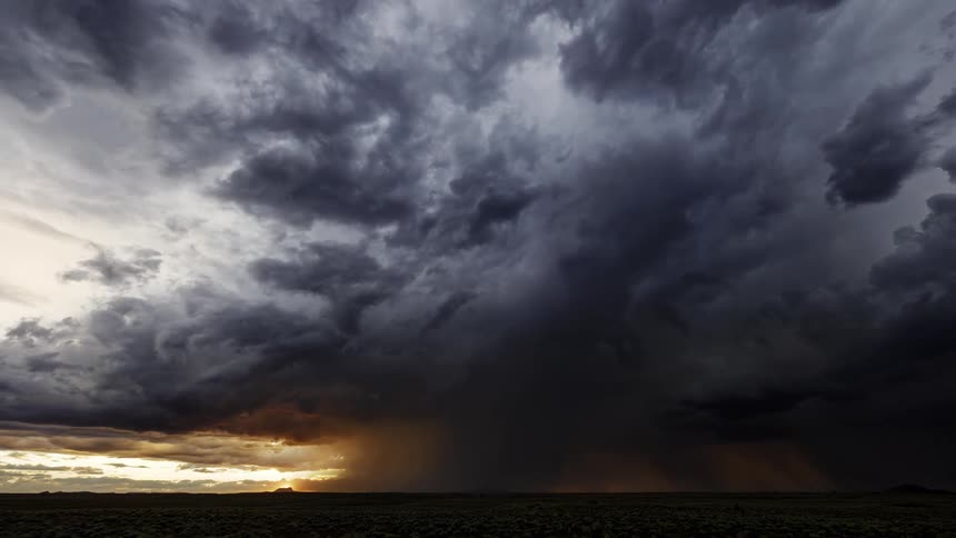 Storm clouds and rain over the plains at sunset
