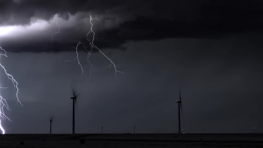 A storm is striking lightning all around the windmills