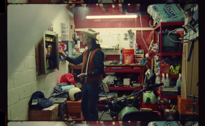 A man standing inside a workshop opening a cabinet door and looking inside