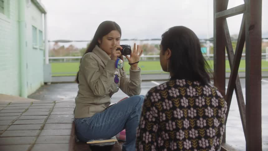 A young girl photographs her friend with a photo camera