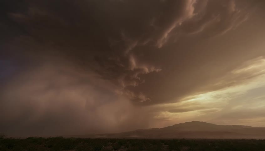 Thunderstorm and a tornado over an area with mountains during dusk or dawn