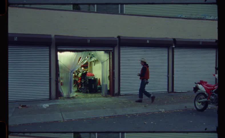 A man in a cowboy hat walks into a small garage