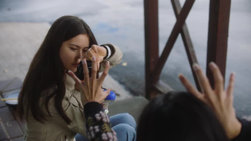 A young woman takes a photo of her friend with a photo camera