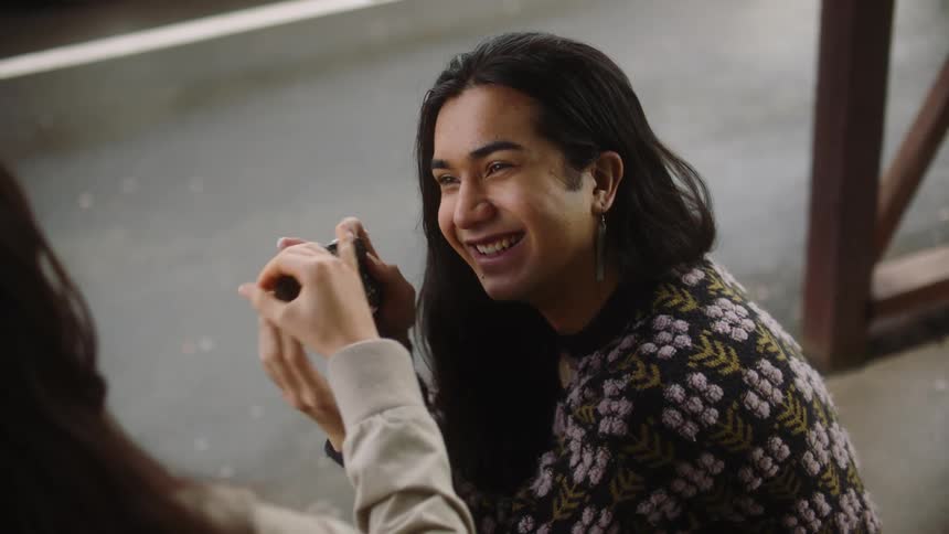Man shows newly taken picture to woman then laughs as they talk