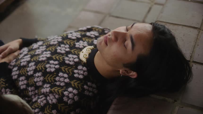 A man with long hair is lying on a staircase and laughing talking to someone