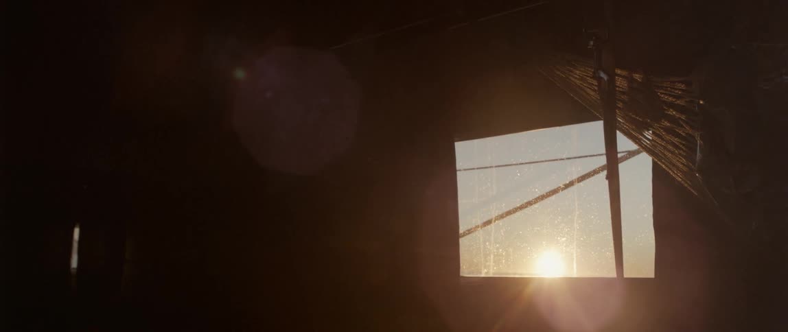 Through the window is water and a setting sun