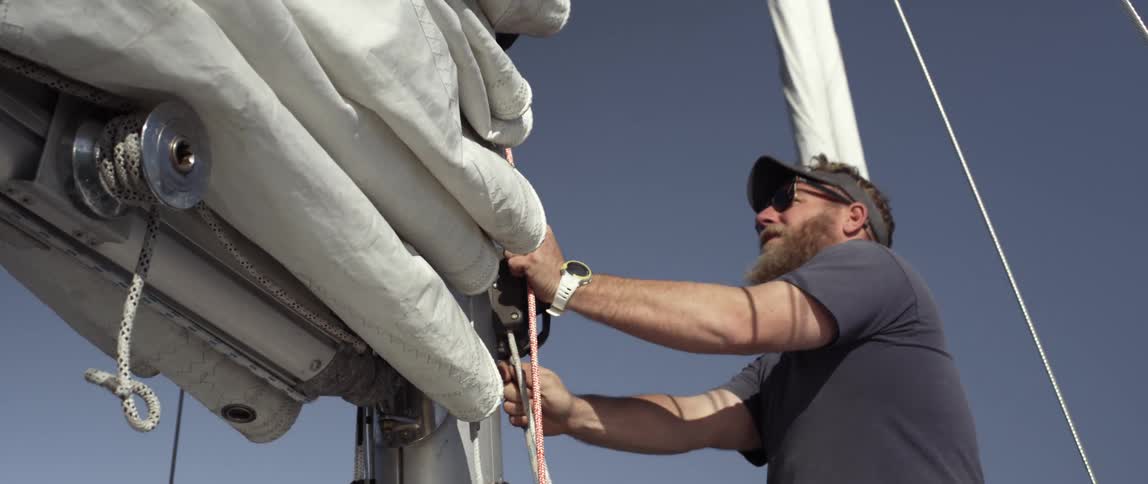 A man is tying sales on a boat