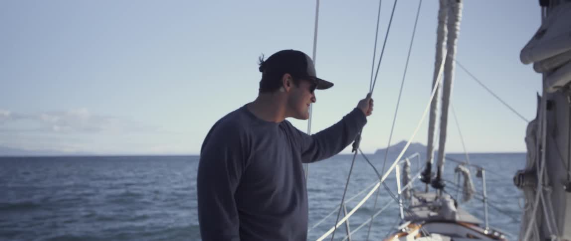 A man is hanging on the rope of a sailing ship