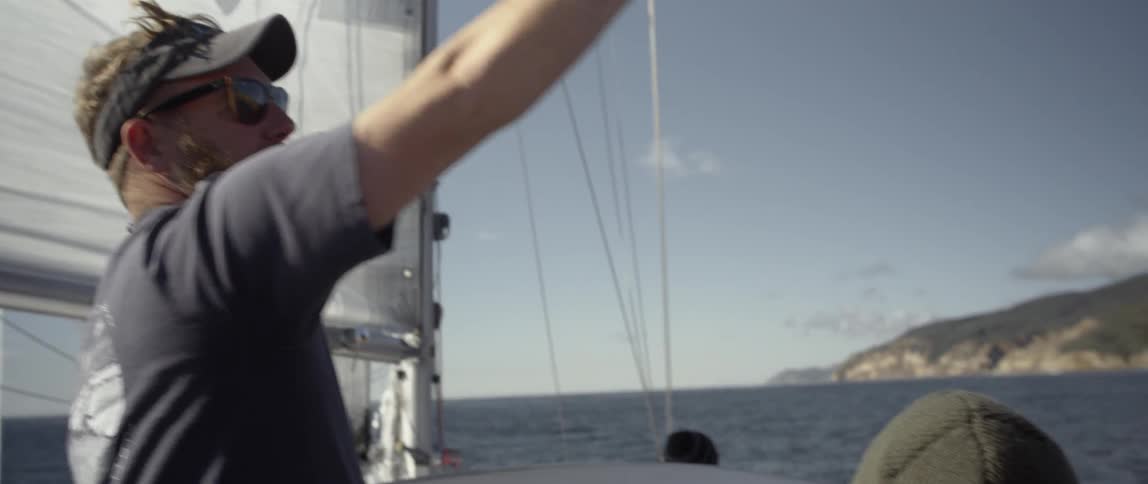 A man on a boat points at something in the distance