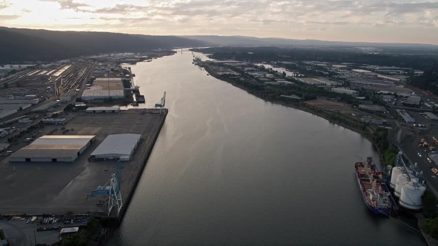 Aerial footage of riverfront warehouses at sunset in Northwest Industrial Portland Oregon with the Willamette River flowing by