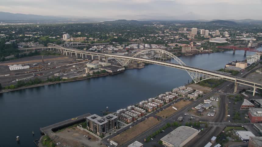  aerial footage of flying over the Fremont Bridge at sunset capturing the beautiful waterfront and downtown skyline of Portland Oregon