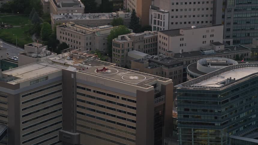 A red helicopter takes off from a helipad on the building of Oregon Health and Science University during a sunset in Portland Oregon