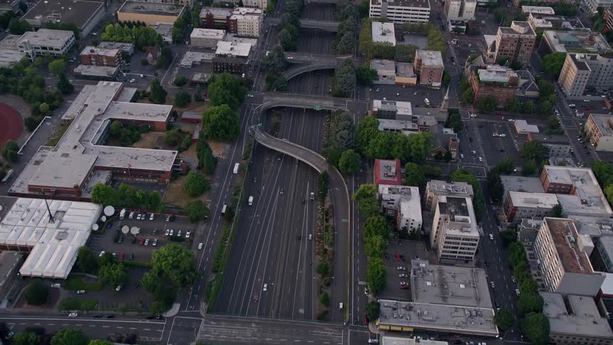 Bird's eye view aerial footage of Downtown Portland Oregon during sunset capturing the Interstate 405 the cityscape and the partially cloudy skies