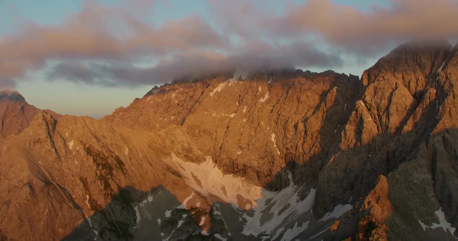 The peak of a rocky mountain is engulfed in thin gray clouds