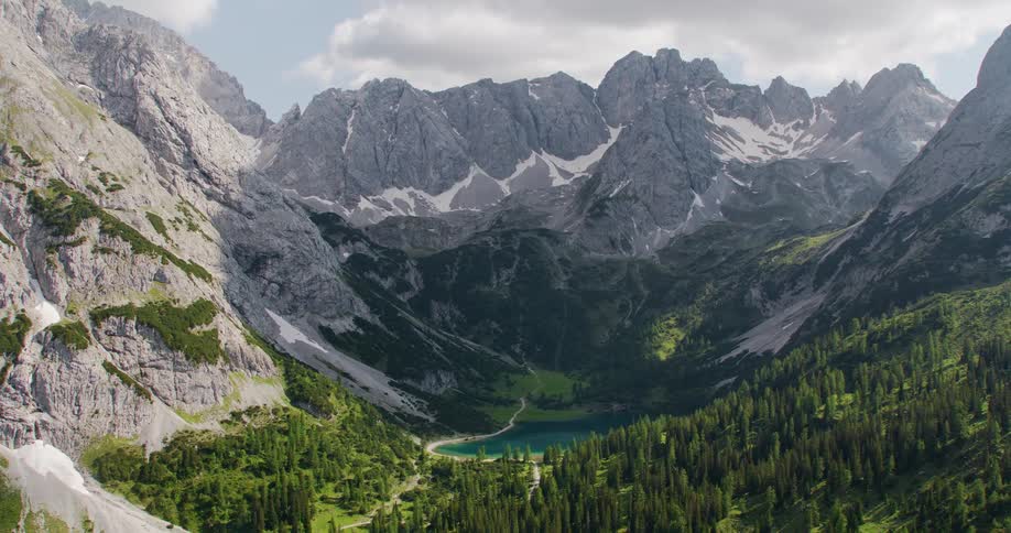 Rocky mountains line a valley filled with evergreen trees and a lake