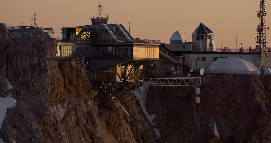 An aerial view of a building complex on the edge of a cliff at dusk