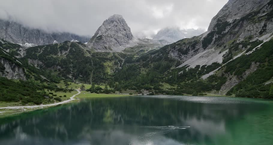 A serene lake is located in a valley surrounded by snowcovered mountains