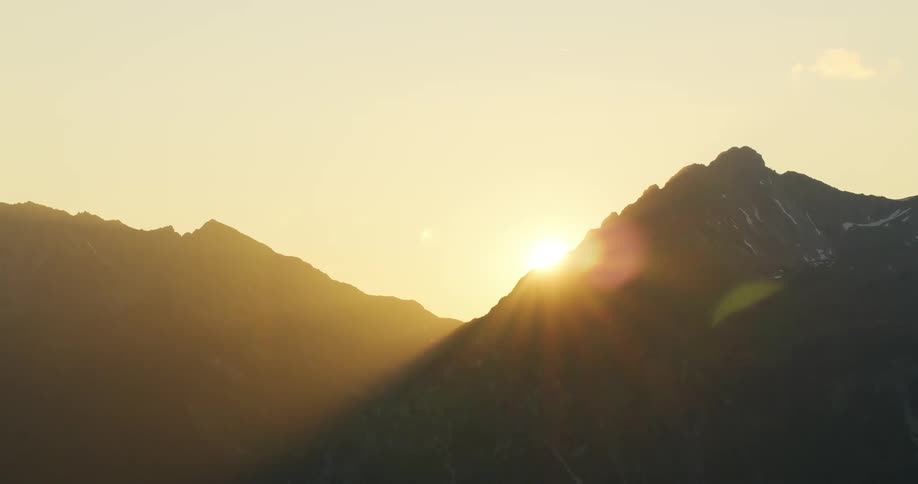 Rays of light shine brightly as the sun is barely visible above the mountains
