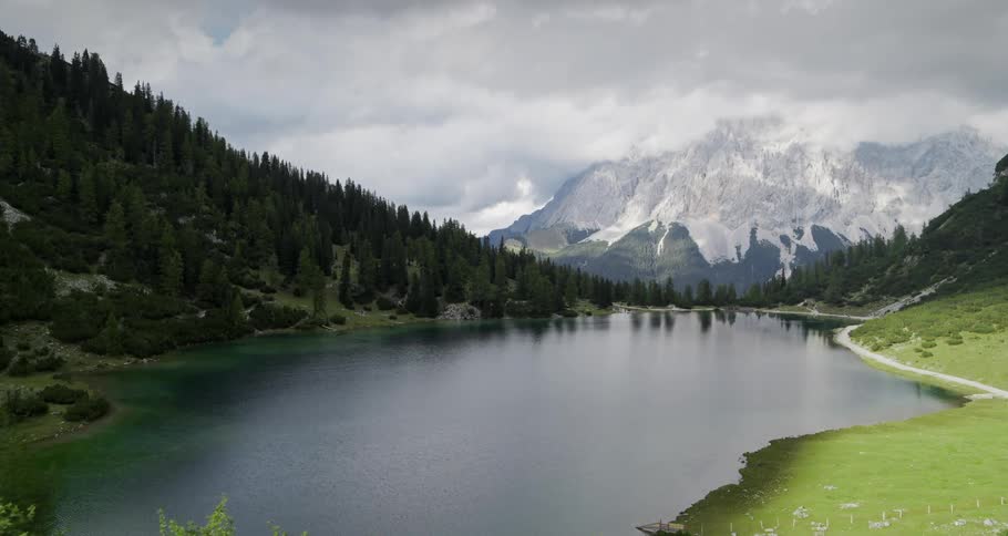 An aerial view of a lake in the middle of hills with forest and vegetation