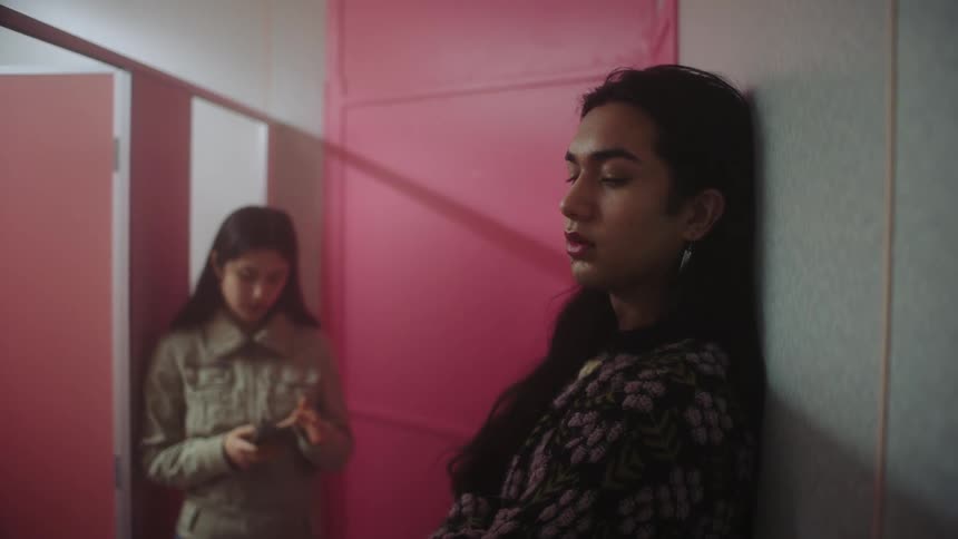 Two people talking with one of them using their cellphone