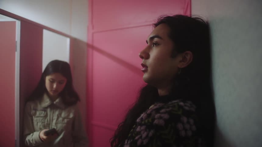 Close up of a teenage girl and boy standing near each other in small area indoors during the day