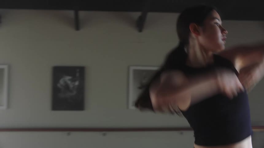 A young woman performs dance steps in a studio