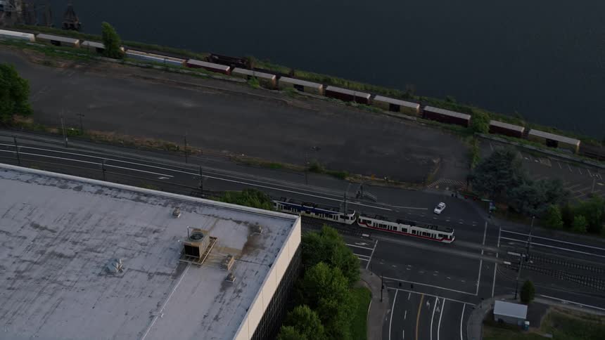 Approaching the Broadway Bridge in North Portland Oregon during sunset this aerial footage tracks a commuter train as it travels over the bridge and reveals stunning views of the city and the Willamette River
