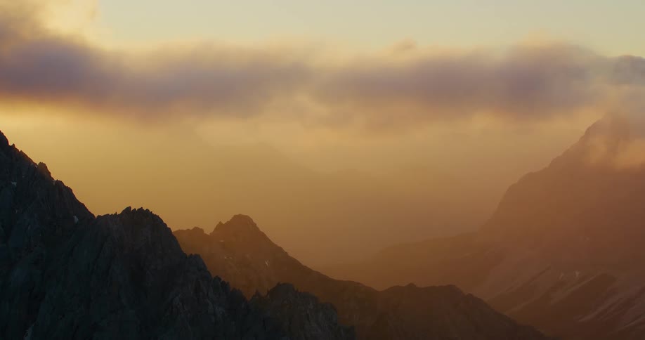 A scenic view of mountains shrouded in cloudy brown hues during the evening