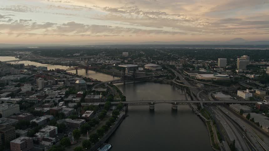 Aerial footage during twilight of Portland Oregon showcasing the Willamette River Rose Garden Arena and Memorial Coliseum as bridges cross the city