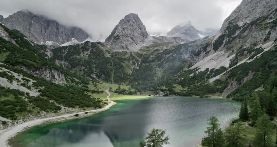 Aerial of a lake surrounded by trees and a mountain with ice