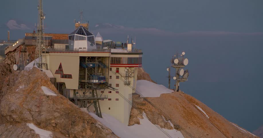 A mountain landscape with a house built on its slopes and satellite dishes installed on the mountain
