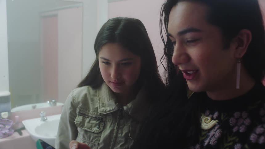 Two young women looking at the cellphone laughing and chatting with each other