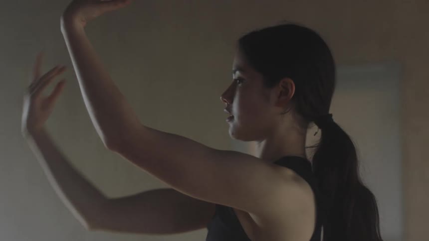 A young girl in a room performing and practicing her dance movement
