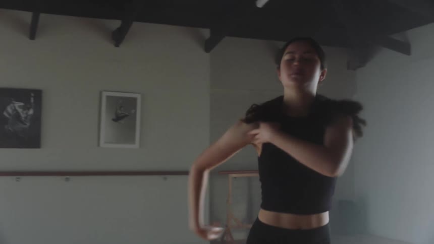 A ballerina on a black top and short practicing ballet moves